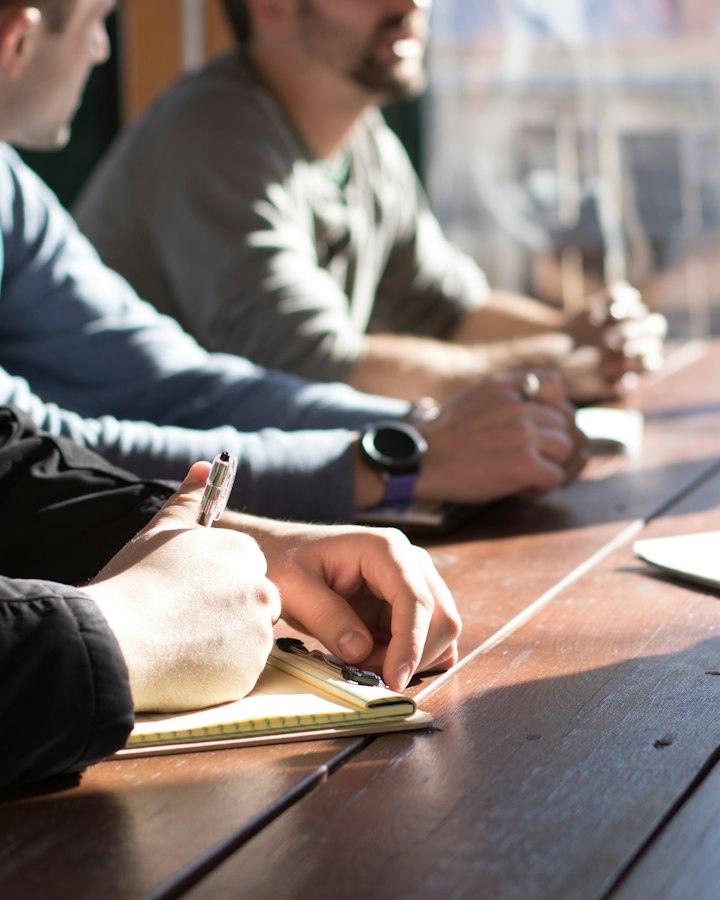 People around a table taking notes during a meeting