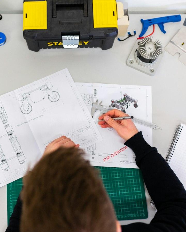 Overhead view of someone sketching technical drawings