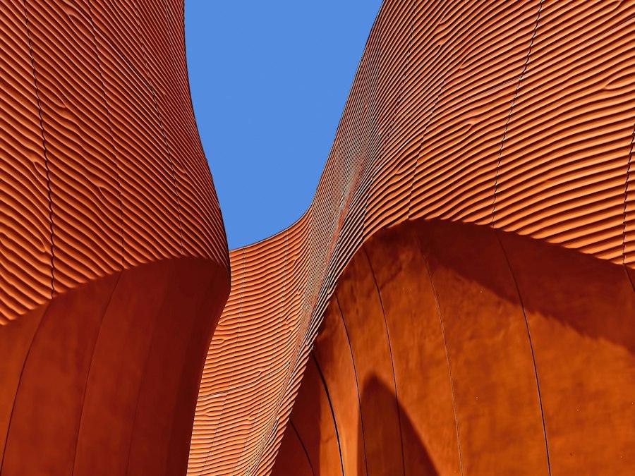 Curved terracotta brick facade against a blue sky