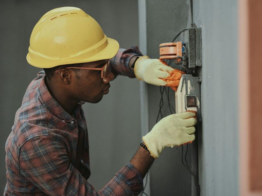 Electrician in a hard hat testing an electrical panel