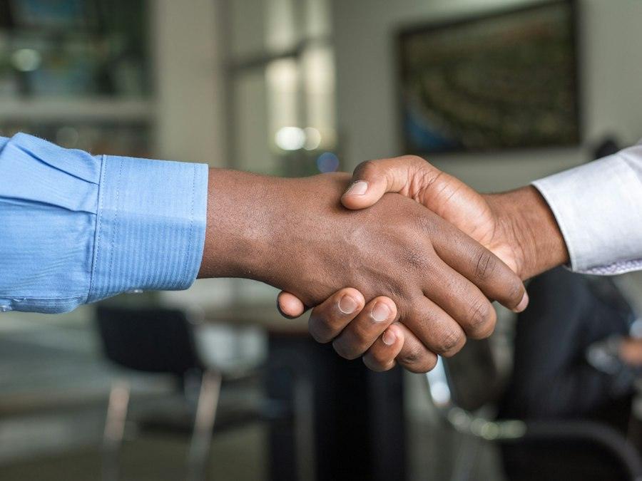 Two people shaking hands across a desk