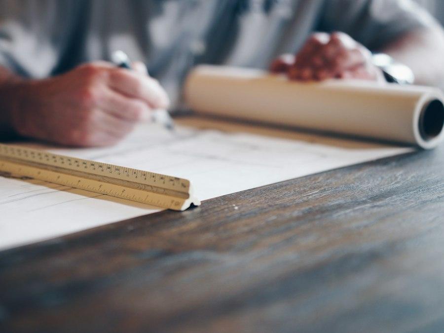 Hand drawing a plan with a scale ruler and rolled drawings